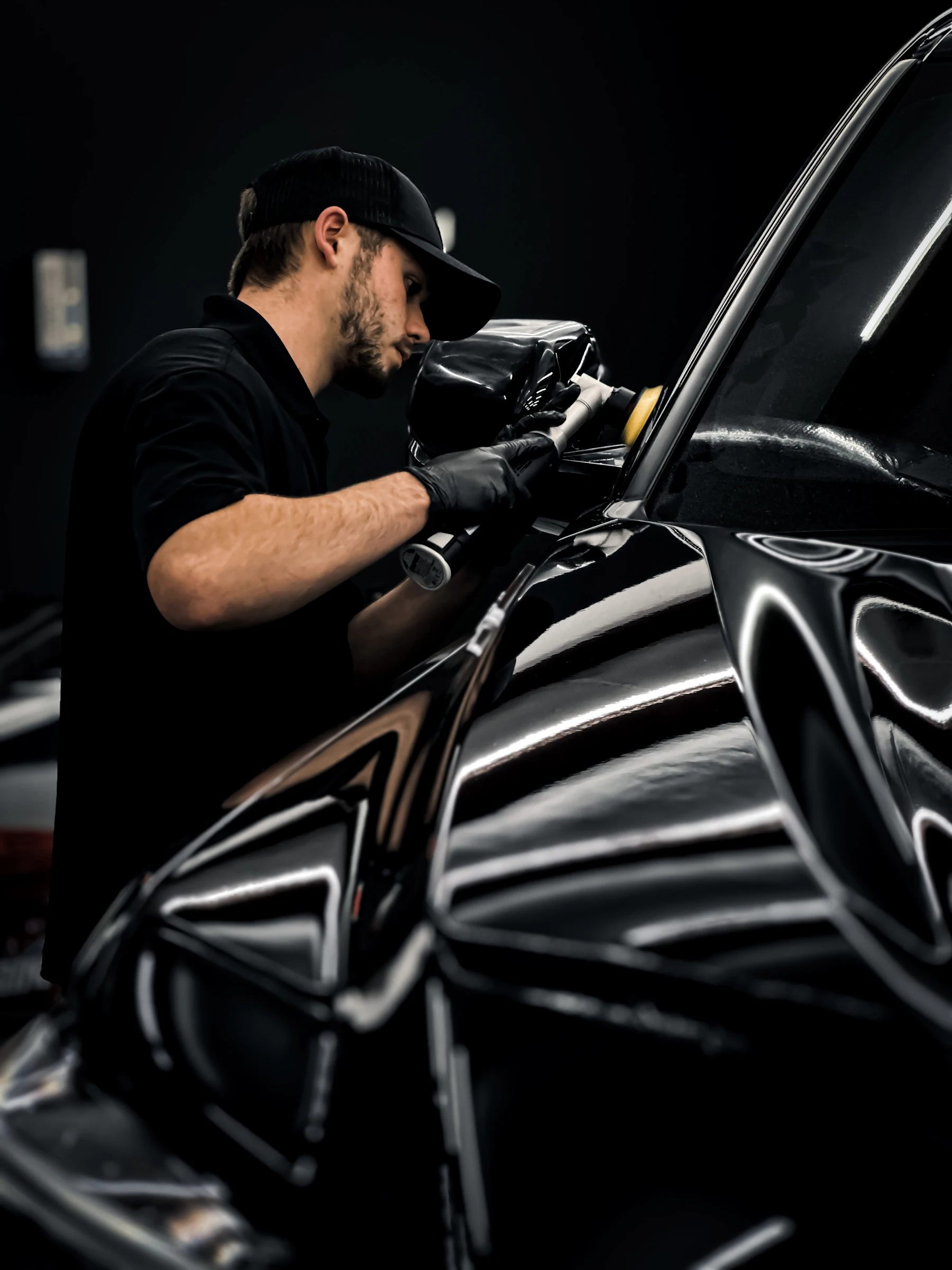 Detailer polishing a black car by hand