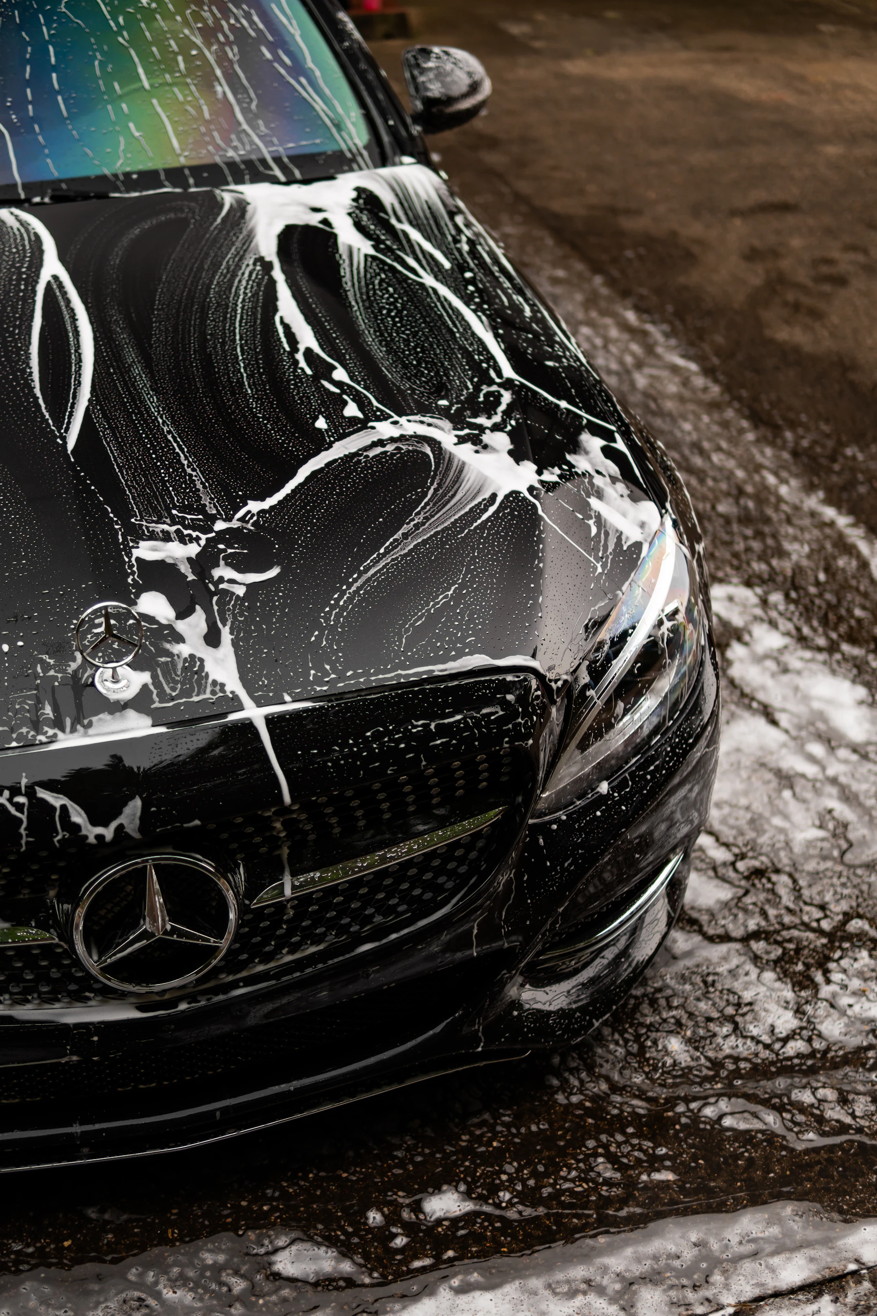 Foam sliding off a dark car bonnet